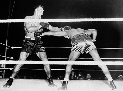 Primo Carnera, left, gasps as Joe Louis reaches his stomach with a stiff left in the third round of their fight at Yankee Stadium, New York, June 25, 1935. (AP Photo)